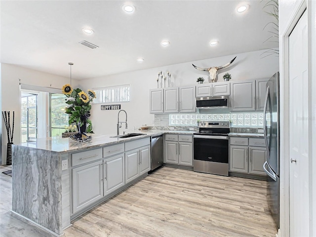 kitchen with kitchen peninsula, appliances with stainless steel finishes, gray cabinetry, and sink