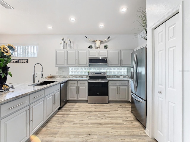 kitchen featuring sink, gray cabinets, light stone countertops, appliances with stainless steel finishes, and tasteful backsplash