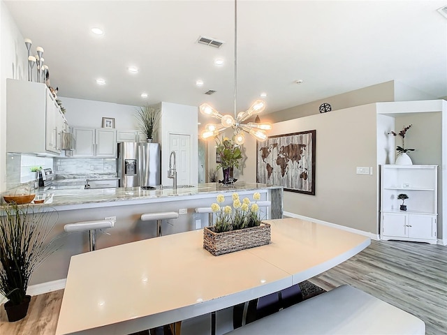 kitchen with sink, stainless steel appliances, backsplash, a breakfast bar, and white cabinets