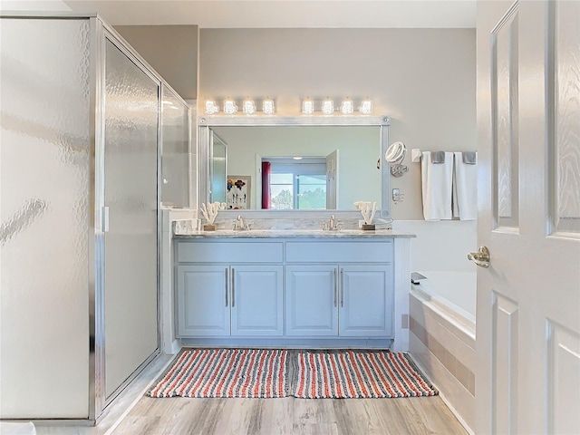 bathroom featuring hardwood / wood-style floors, vanity, and plus walk in shower