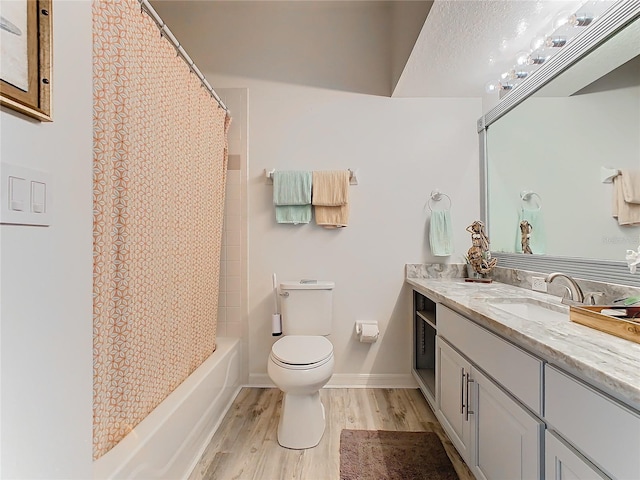 full bathroom with vanity, a textured ceiling, shower / bath combo with shower curtain, hardwood / wood-style floors, and toilet