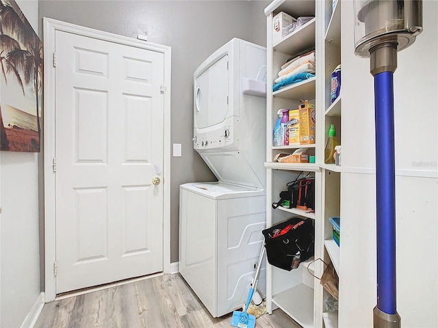 laundry area featuring stacked washer / dryer and light hardwood / wood-style flooring