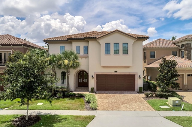 mediterranean / spanish home featuring a garage and a front lawn