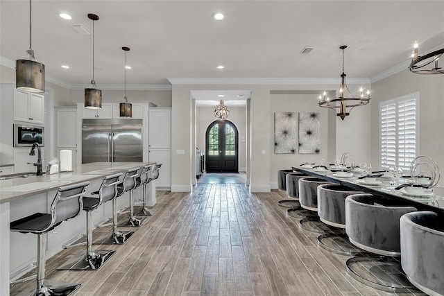 kitchen with built in appliances, white cabinetry, sink, and light wood-type flooring