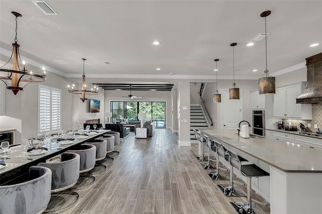 kitchen featuring white cabinets, pendant lighting, ceiling fan with notable chandelier, and light hardwood / wood-style floors