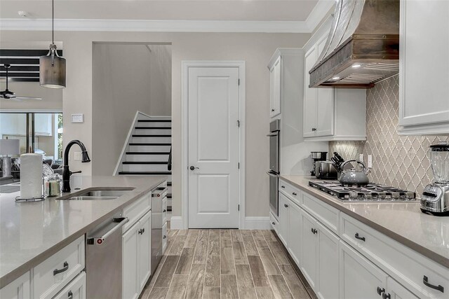 kitchen featuring custom range hood, sink, pendant lighting, light hardwood / wood-style floors, and white cabinetry