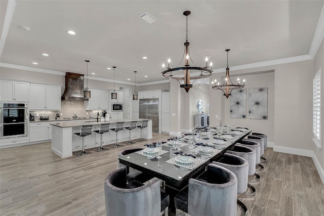 dining room featuring crown molding, a notable chandelier, and light wood-type flooring