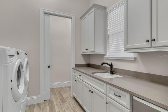 clothes washing area featuring washer and dryer, cabinets, sink, and light hardwood / wood-style flooring