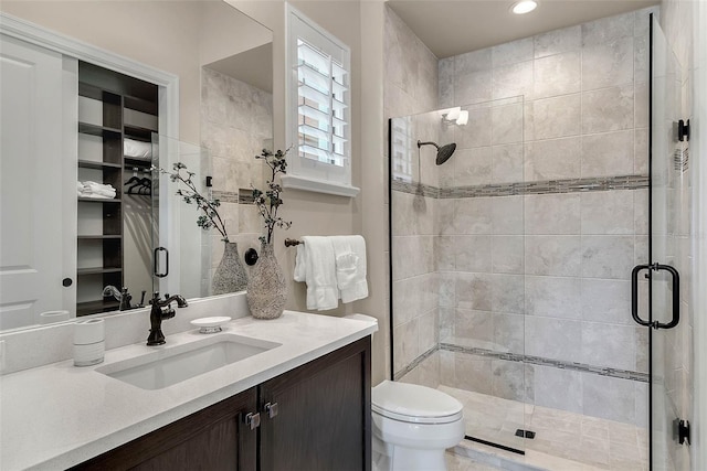 bathroom featuring a shower with door, vanity, and toilet