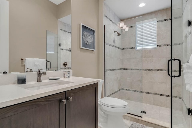 bathroom featuring vanity, a shower with shower door, and toilet