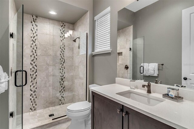 bathroom featuring vanity, toilet, and a shower with shower door