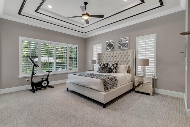 carpeted bedroom with a raised ceiling, ceiling fan, and crown molding