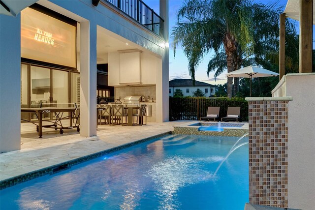 view of swimming pool with an in ground hot tub, an outdoor kitchen, pool water feature, and a patio area