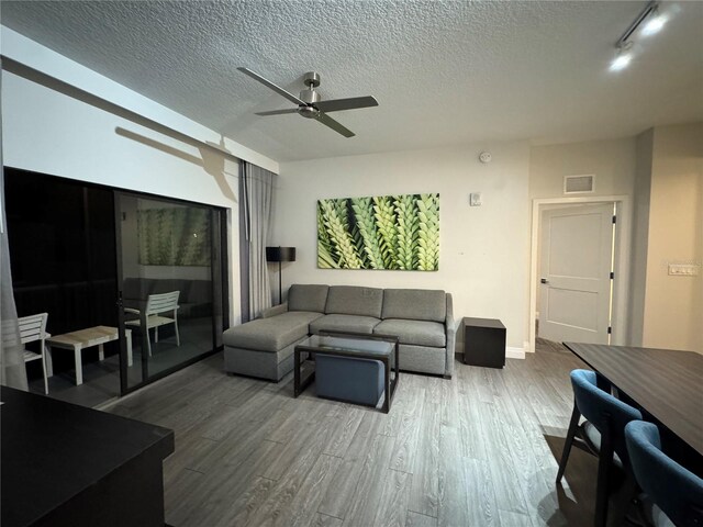 living room featuring hardwood / wood-style floors, ceiling fan, and a textured ceiling