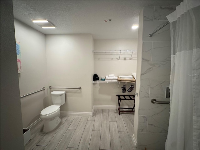 bathroom featuring a shower with curtain, toilet, wood-type flooring, and a textured ceiling