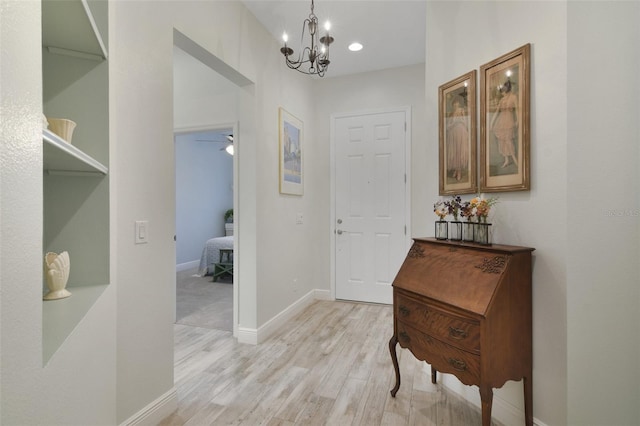 hallway with light hardwood / wood-style flooring and a chandelier