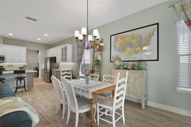 dining area with a wealth of natural light, an inviting chandelier, and light wood-type flooring