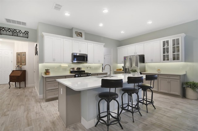 kitchen with gray cabinetry, stainless steel appliances, sink, and a kitchen breakfast bar