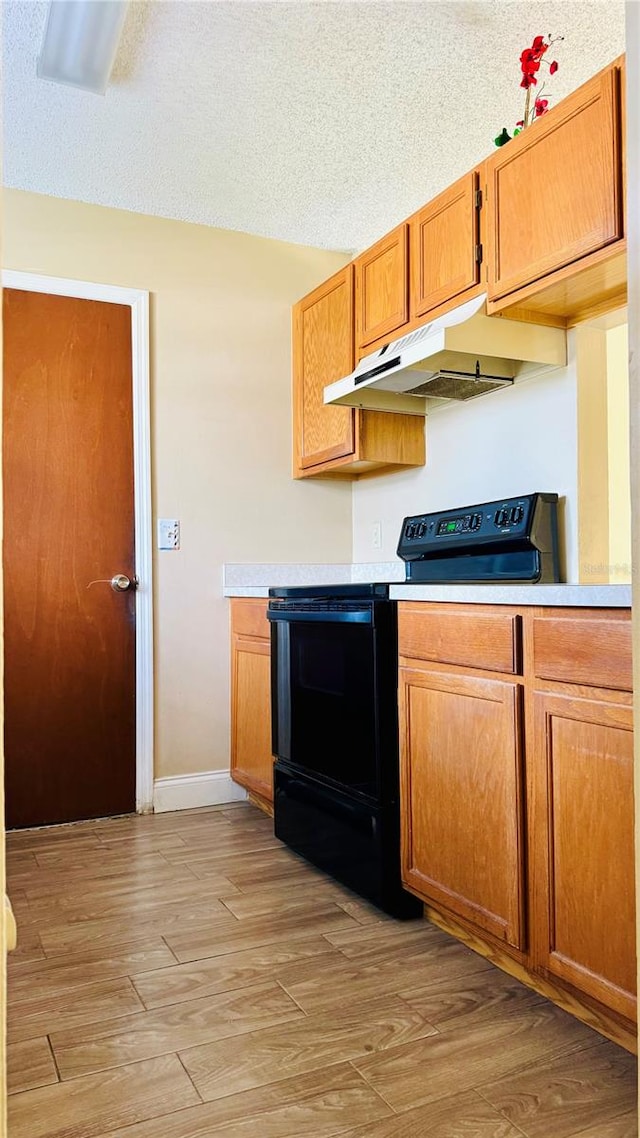 kitchen with black electric range oven, a textured ceiling, and light wood-type flooring