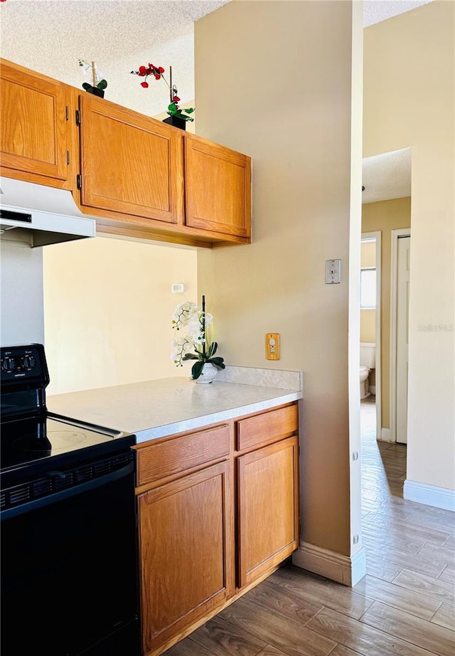 kitchen with black electric range, a textured ceiling, and dark hardwood / wood-style floors