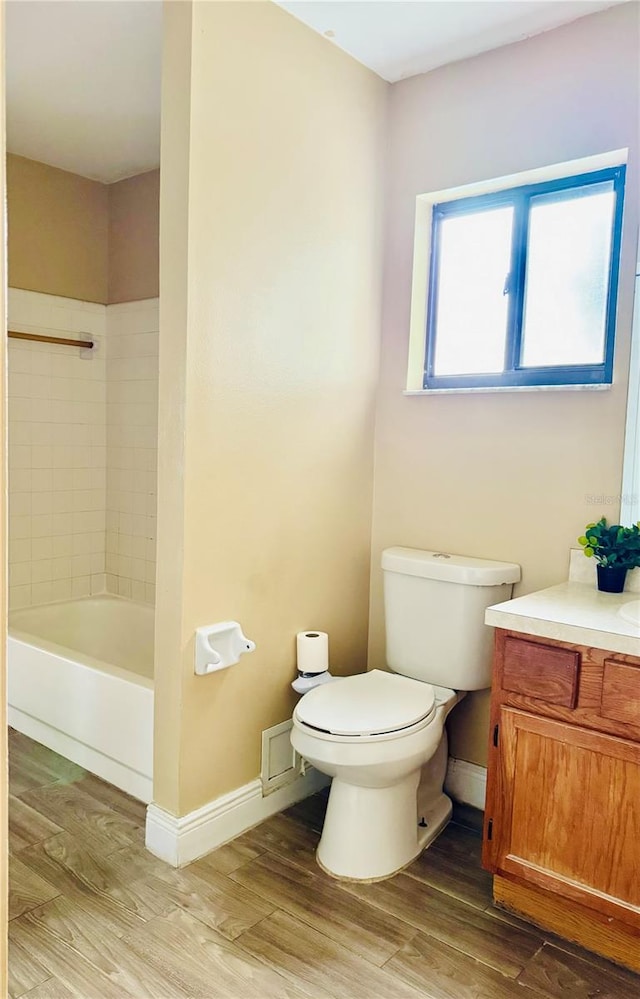 full bathroom with toilet, hardwood / wood-style floors, tiled shower / bath combo, and vanity