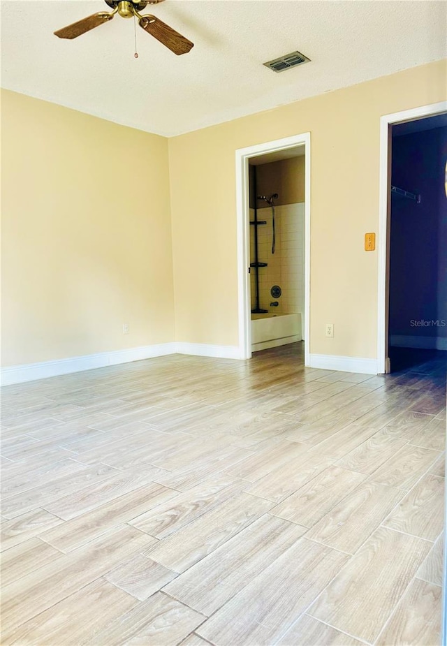 spare room with light hardwood / wood-style flooring, a textured ceiling, and ceiling fan