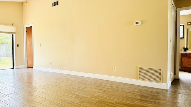 empty room with a towering ceiling and light hardwood / wood-style flooring