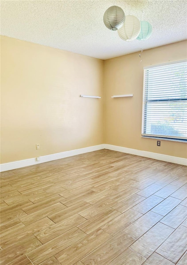 unfurnished room with a textured ceiling and light wood-type flooring