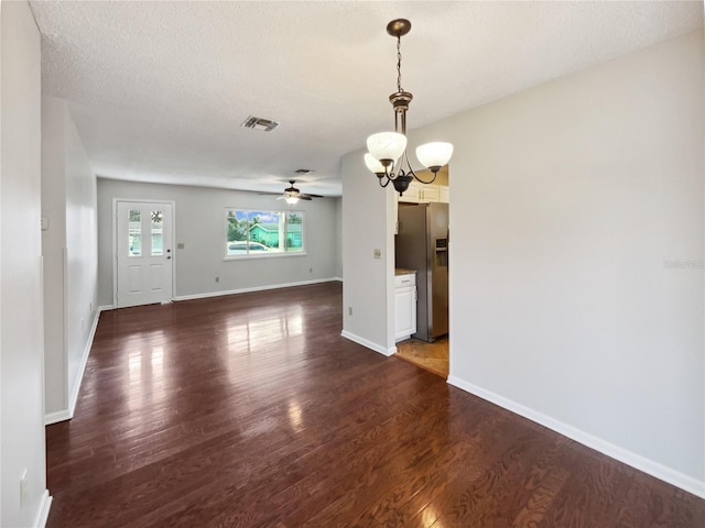 interior space featuring ceiling fan with notable chandelier, a textured ceiling, and dark hardwood / wood-style floors