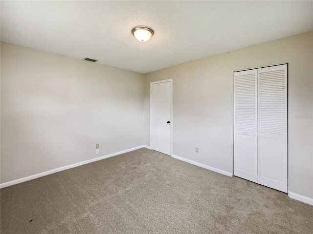 unfurnished bedroom featuring a closet, a textured ceiling, and carpet flooring