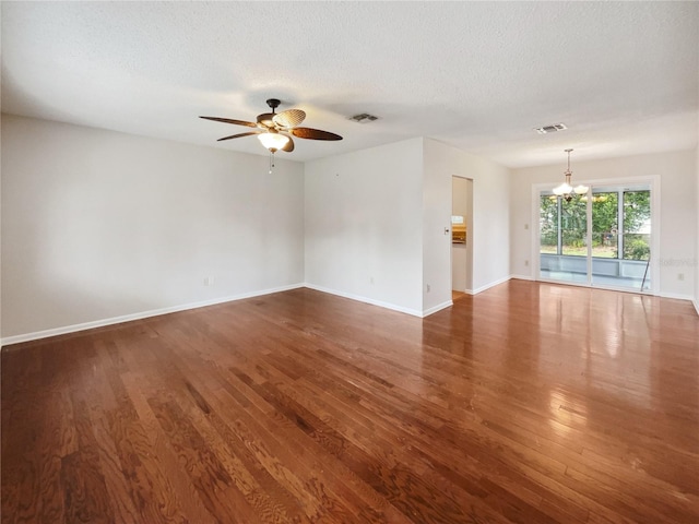 empty room featuring dark hardwood / wood-style floors, a textured ceiling, and ceiling fan with notable chandelier