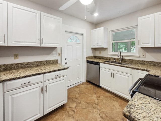 kitchen with stainless steel dishwasher, sink, white cabinets, and dark stone counters