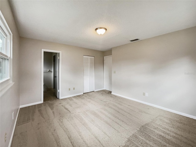 unfurnished bedroom featuring light carpet and a textured ceiling