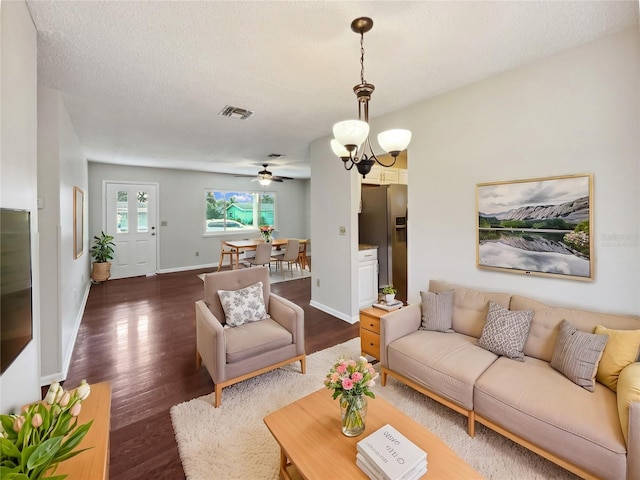 living room with a textured ceiling, ceiling fan with notable chandelier, and dark hardwood / wood-style flooring