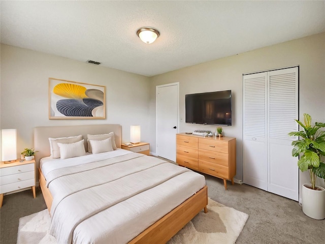 bedroom with a textured ceiling, light colored carpet, and a closet