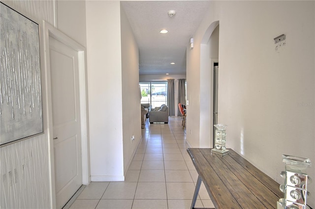 corridor featuring a textured ceiling and light tile patterned floors