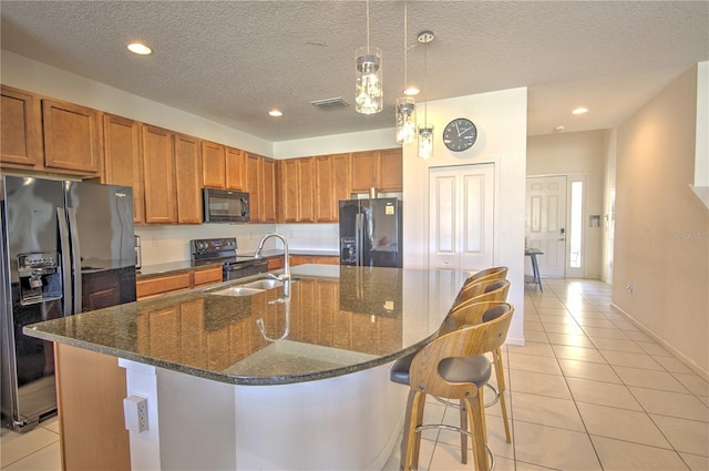 kitchen featuring light tile patterned flooring, a center island with sink, sink, black appliances, and a textured ceiling