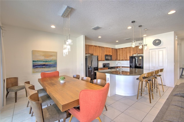 kitchen featuring pendant lighting, a center island with sink, sink, and black appliances