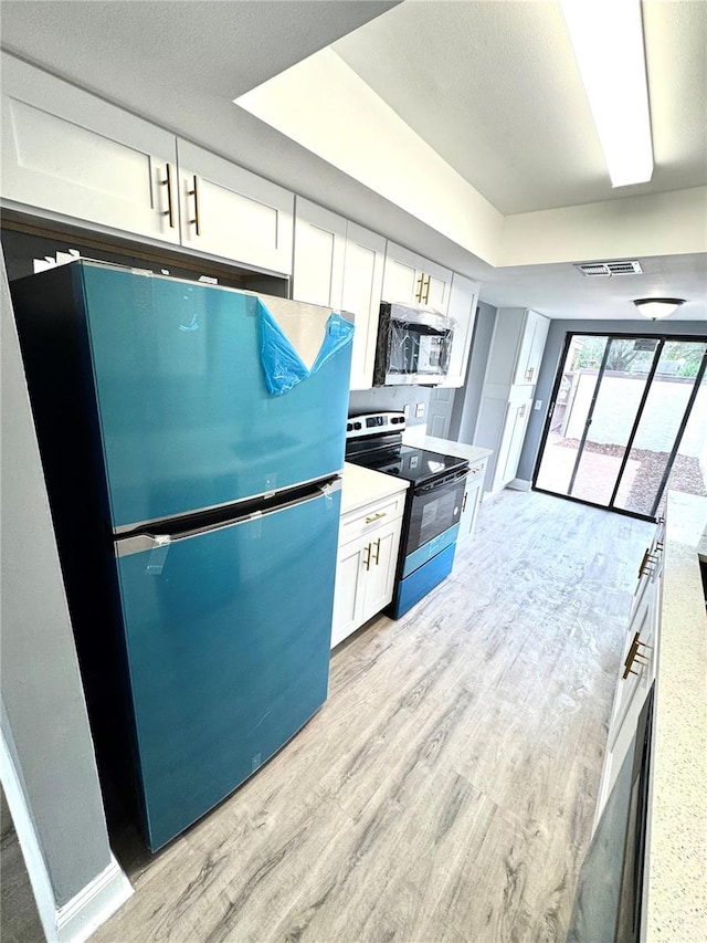 kitchen with light hardwood / wood-style flooring, white cabinets, and stainless steel appliances