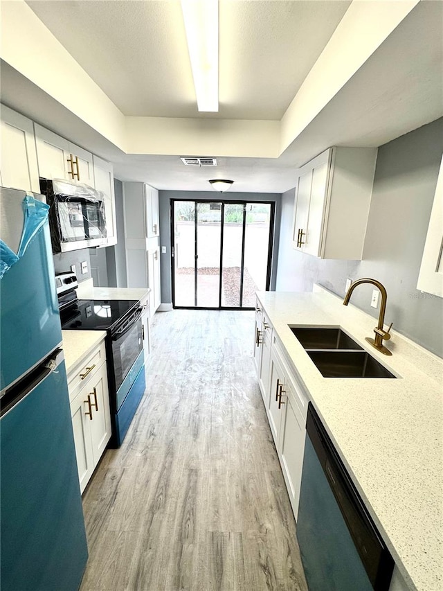 kitchen with white cabinetry, light hardwood / wood-style flooring, stainless steel appliances, and sink