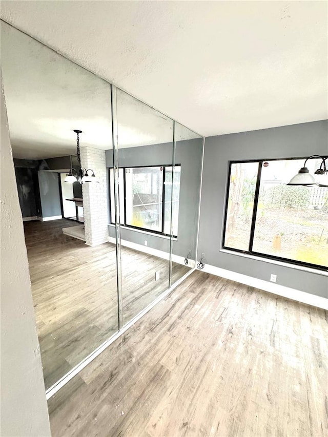 unfurnished bedroom featuring a chandelier, multiple windows, and hardwood / wood-style flooring