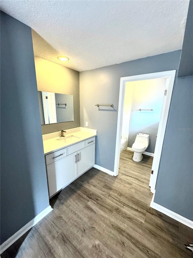 bathroom with vanity, toilet, hardwood / wood-style flooring, and a textured ceiling