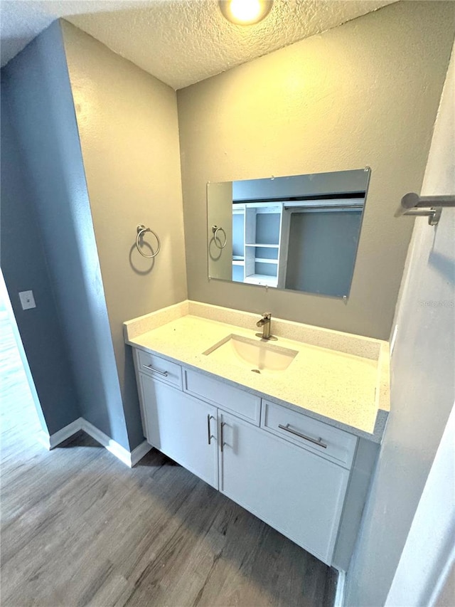 bathroom with vanity, wood-type flooring, and a textured ceiling