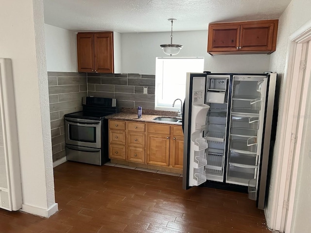 kitchen with tile walls, appliances with stainless steel finishes, pendant lighting, sink, and dark wood-type flooring