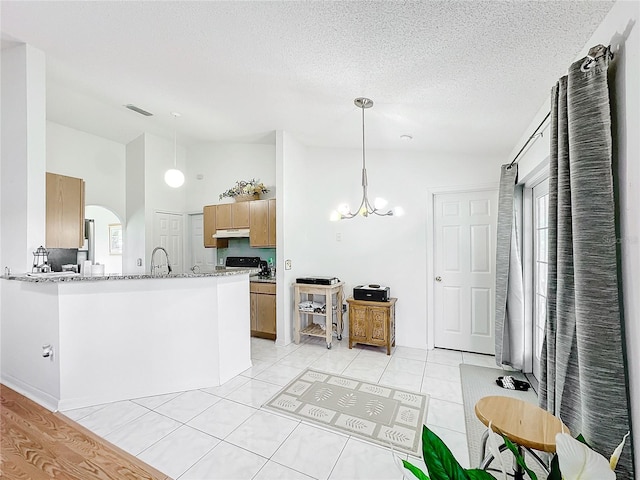 kitchen featuring light stone countertops, high vaulted ceiling, a chandelier, sink, and decorative light fixtures