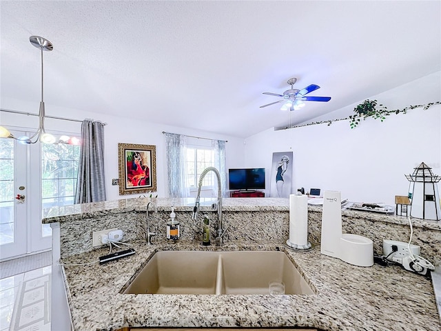 kitchen featuring sink, light stone countertops, vaulted ceiling, pendant lighting, and ceiling fan