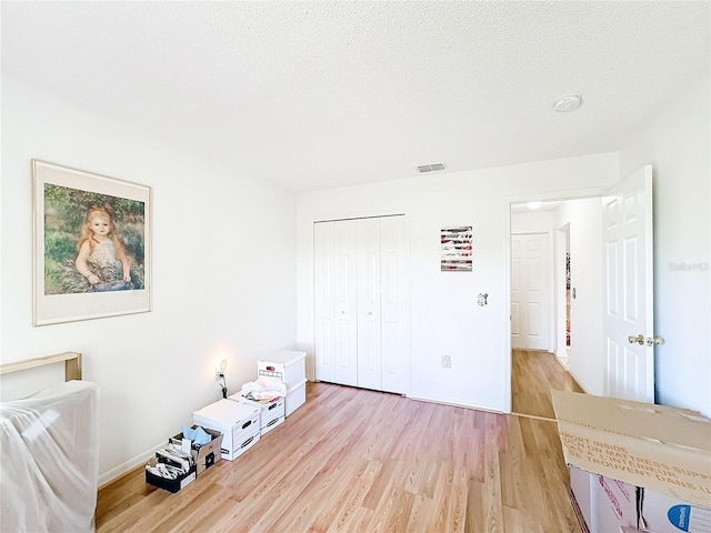 unfurnished bedroom featuring a textured ceiling, light wood-type flooring, and a closet