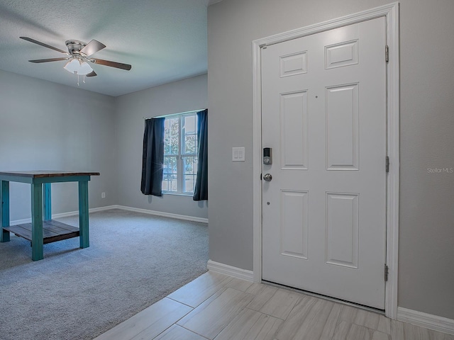 carpeted entrance foyer with a textured ceiling and ceiling fan