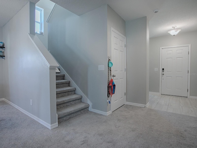 entryway with light colored carpet and a textured ceiling