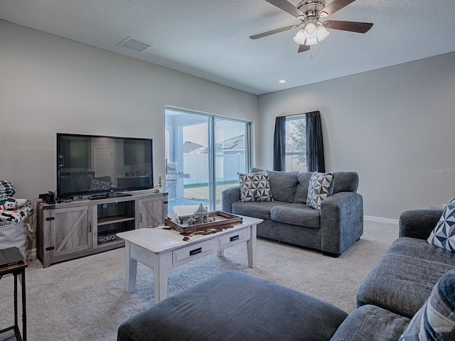 carpeted living room with ceiling fan and a textured ceiling